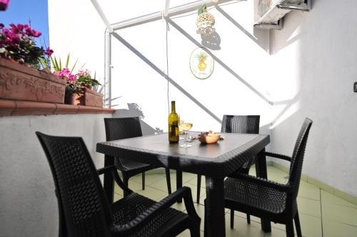 a table with chairs and a bottle of wine on it at B&b Le Cycas in Castellammare di Stabia