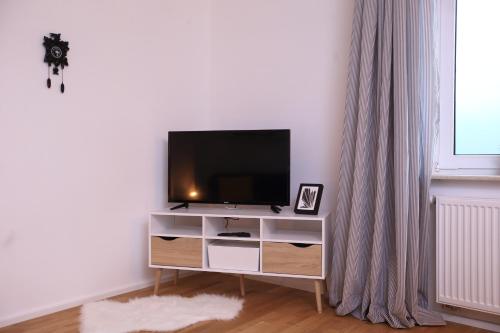 a living room with a television on a white cabinet at 1Step2AllCities House&Garden in Wuppertal