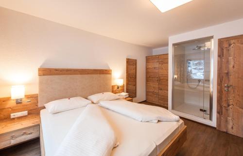 a bedroom with a white bed and a glass shower at Ferienhaus Larinmos in Lermoos