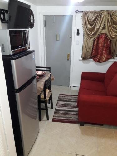 a living room with a refrigerator and a red couch at Studio, One and Two Bedroom Apartments - Bronx in Bronx