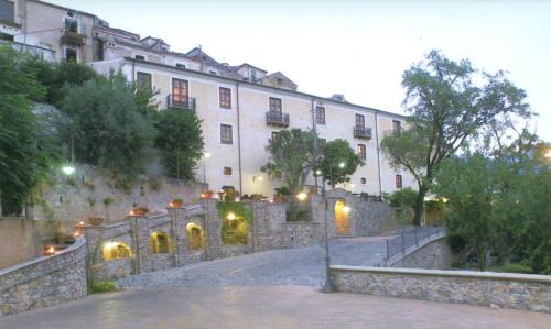 duży biały budynek z kamienną ścianą i schodami w obiekcie Villa San Domenico w mieście Morano Calabro