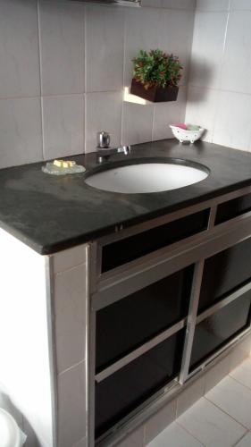a bathroom with a sink and a black counter at Quarto e suíte para uma pessoa in Alfenas