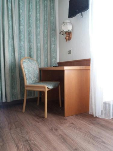 a chair sitting next to a desk in a room at Hotel Ottoz Meublé in Courmayeur