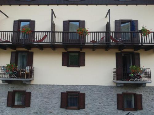 a building with windows and balconies with flowers on them at Hotel Ottoz Meublé in Courmayeur