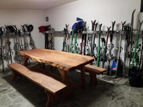 a room with a wooden table and a bunch of skis at Hotel Ottoz Meublé in Courmayeur