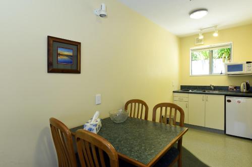 a kitchen with a table and chairs and a kitchen with a refrigerator at Abelia Motor Lodge in Nelson