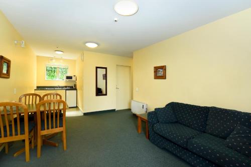 a living room with a couch and a table and a kitchen at Abelia Motor Lodge in Nelson