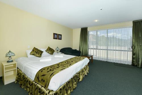 a bedroom with a large bed and a large window at Abelia Motor Lodge in Nelson