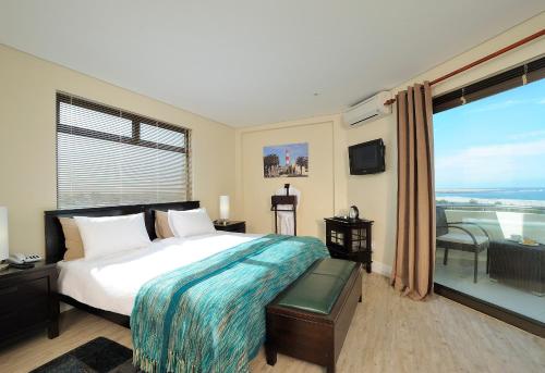 a bedroom with a large bed and a large window at Beach Hotel Swakopmund in Swakopmund