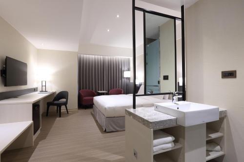 a hotel room with a bed and a sink and a mirror at Full Kind Hotel in Hualien City