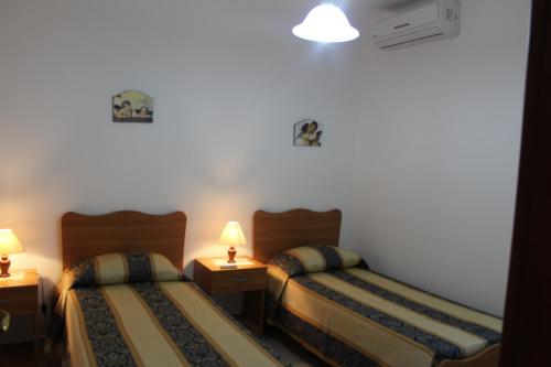 una camera d'albergo con due letti e due lampade di Villetta/Appartamento Mahia2 a Torre Suda