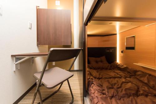 a chair and a bed in a small room at Ryoma Ikebukuro in Tokyo