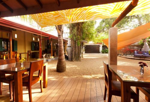 a patio with tables and chairs and a yellow umbrella at Dickman Resort "The Boutique Hotel" in Negombo