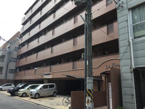a parking lot with cars parked in front of a building at Laforet Tokaichi in Hiroshima