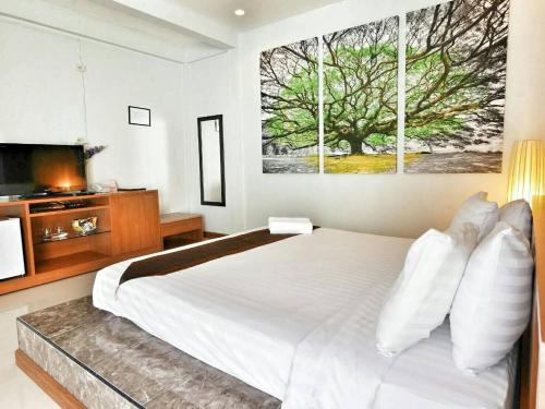 a bedroom with a large white bed with a television at The Vista Pool Villa in Kanchanaburi