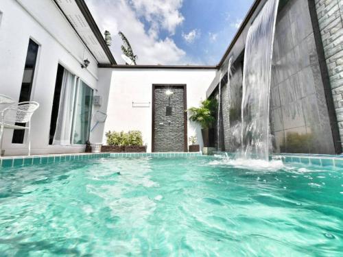 a swimming pool with a waterfall in a house at The Vista Pool Villa in Kanchanaburi