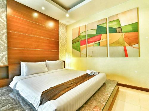 a bedroom with a bed with a painting on the wall at The Vista Pool Villa in Kanchanaburi