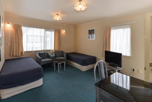 a hotel room with two beds and a flat screen tv at Geneva Motor Lodge in Rotorua