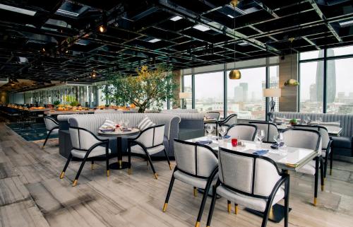 a restaurant with tables and chairs and windows at New Orient Hotel Da Nang in Da Nang