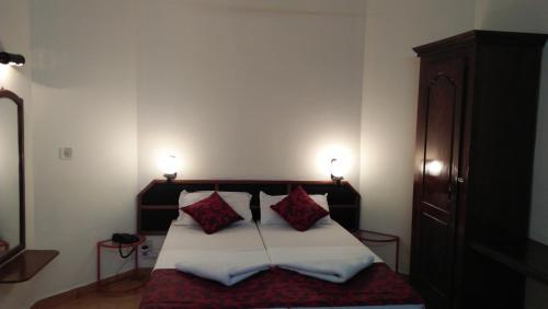 a bedroom with a bed with two red pillows at Hotel Thushara in Kovalam