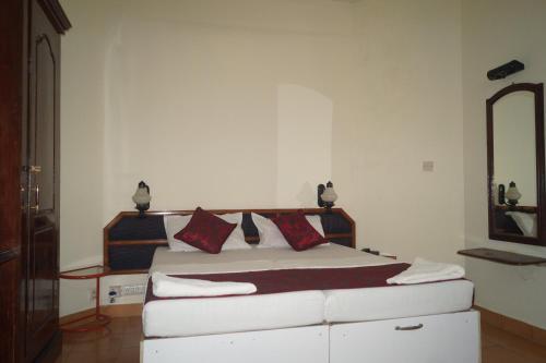 a bedroom with a white bed with red pillows at Hotel Thushara in Kovalam