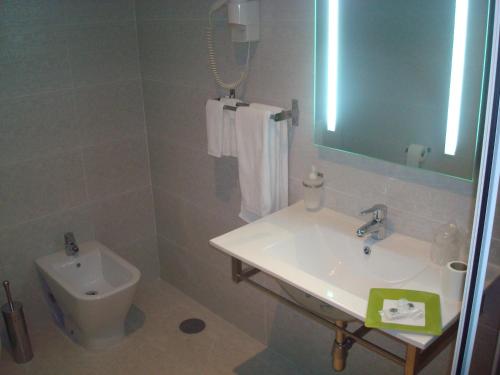 a bathroom with a sink and a toilet and a mirror at Palace Hotel & Spa Termas de São Tiago in Penamacor