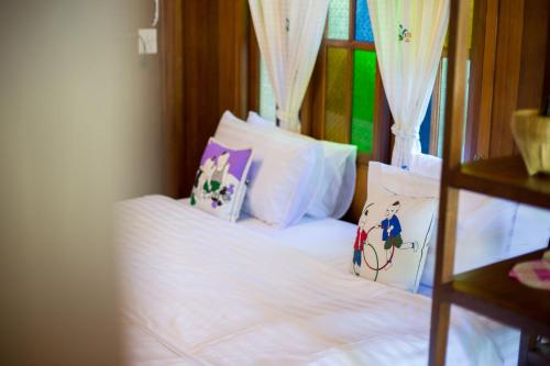 a bedroom with a bed with white sheets and pillows at Suksatan Lamphun in Lamphun