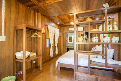 a bedroom with wooden walls and a bed and shelves at Suksatan Lamphun in Lamphun