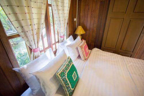 a bedroom with a bed with white pillows and a window at Suksatan Lamphun in Lamphun