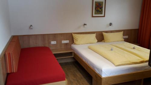a small bedroom with a bed and a red bench at Wurlerhof in Kals am Großglockner
