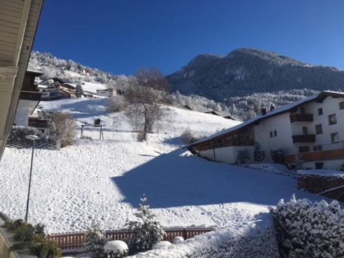 a snow covered yard with a house and a mountain at Ferienwohnung Stuibenfall in Jerzens