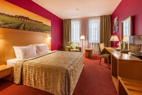 チュメニにあるEurasia Business Hotel Tyumenのベッドとデスクが備わるホテルルームです。