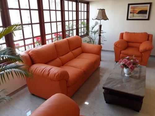 an orange couch and two chairs in a living room at Setrac Orange Hotel in Navi Mumbai