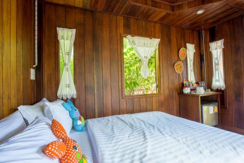 a bedroom with a bed with wooden walls and a window at Suksatan Lamphun in Lamphun
