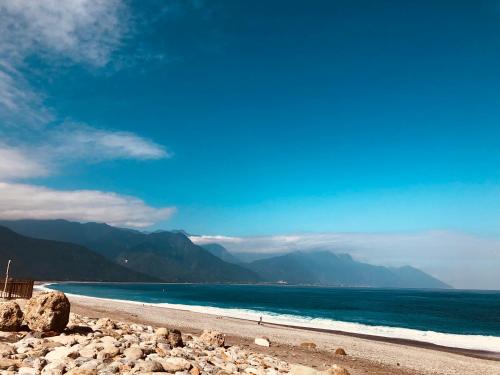 a beach with the ocean and mountains in the background at Rainbow B&B in Dahan