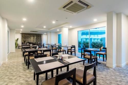 a dining room with tables and chairs and windows at Chada@Nakhon in Nakhon Si Thammarat