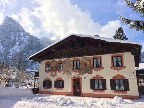 a house in the snow with a mountain in the background at Ferienwohnungen im Lüftlmalereck, Mussldomahaus in Oberammergau