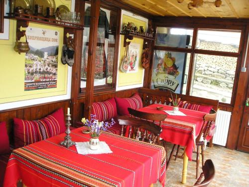 a restaurant with two tables with red table cloth at Guest House Bolyarka in Koprivshtitsa