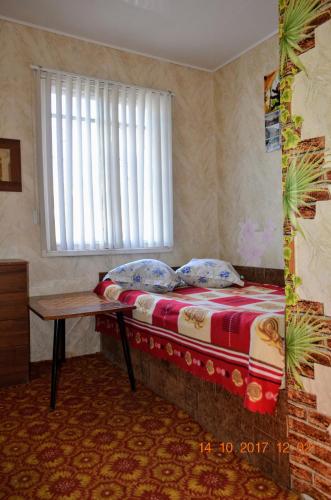 a bedroom with a bed with a table and a window at Petrovskaya Pristan in Cholpon-Ata
