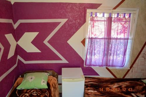 a bedroom with a purple wall and a window at Petrovskaya Pristan in Cholpon-Ata