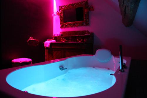 a bathroom with a large tub with pink lighting at L'Hibernie in Rochefort-en-Yvelines