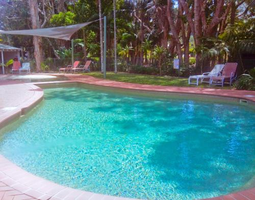 a large pool with blue water in a yard at Beach Resort Apartment in Port Macquarie