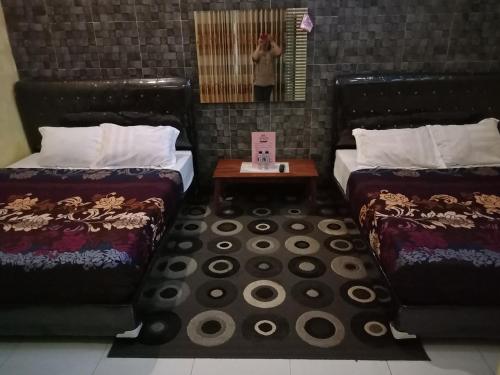 a person taking a picture of two beds in a room at Penginapan & Guest House Mbok Dhe Borobudur in Borobudur