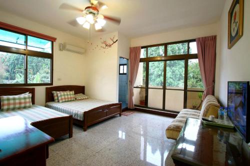a living room with two beds and a couch and windows at 鋐洋民宿 in Lugu