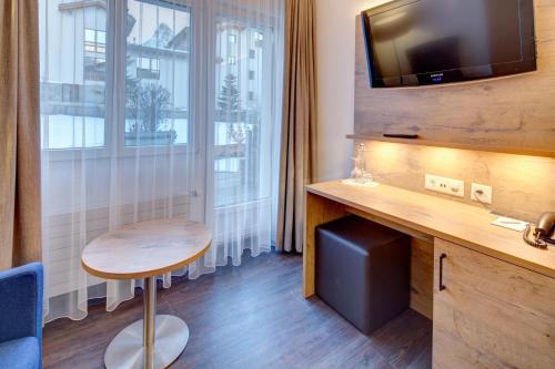 ツェルマットにあるAlpen Resort & Spaのデスク、テーブル、窓が備わる客室です。