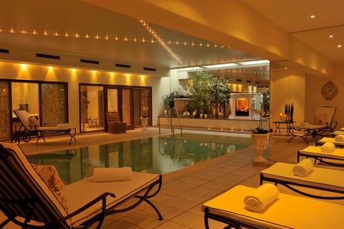 uma piscina num hotel com cadeiras e mesas em Schlosshotel Burg Schlitz em Hohen Demzin