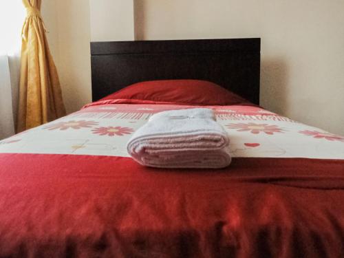a red and white bed with a red and white blanket at Hostal La Rosa Otavalo in Otavalo