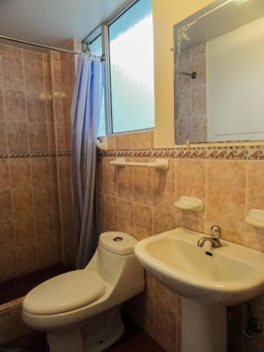 a bathroom with a toilet and a sink at Hostal La Rosa Otavalo in Otavalo