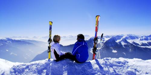 two people sitting on top of a mountain with skis at Pension Aichner in Terento