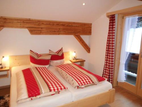 ein Schlafzimmer mit einem Bett mit roten und weißen Kissen in der Unterkunft Seewiesenalm in Reit im Winkl